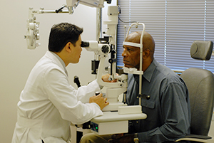 Heath care provider examining man's eyes.