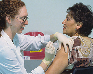 Mature woman getting injection in upper arm.